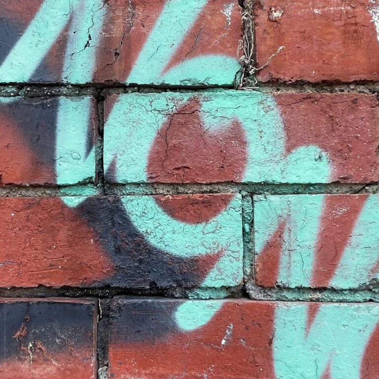 Pale teal spray-painted numerals over weathered red brick, Melbourne inner north, hidden__north documentary photography