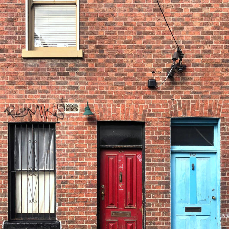 Red and blue doors on a brick terrace, Fitzroy, Melbourne inner north, hidden__north documentary photography