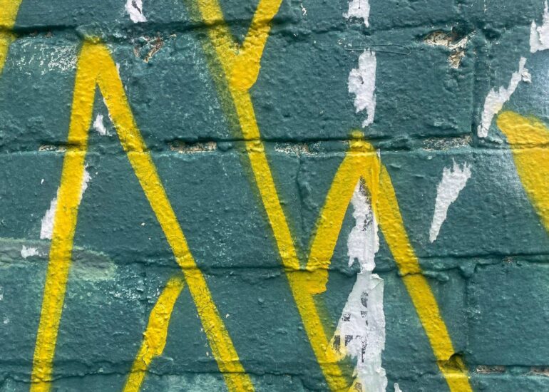 Yellow spray-painted lines over dark green painted brick, Melbourne inner north, hidden__north documentary photography