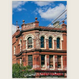 Red brick corner building with arched windows and parapet urns, Melbourne inner north, hidden__north documentary photography