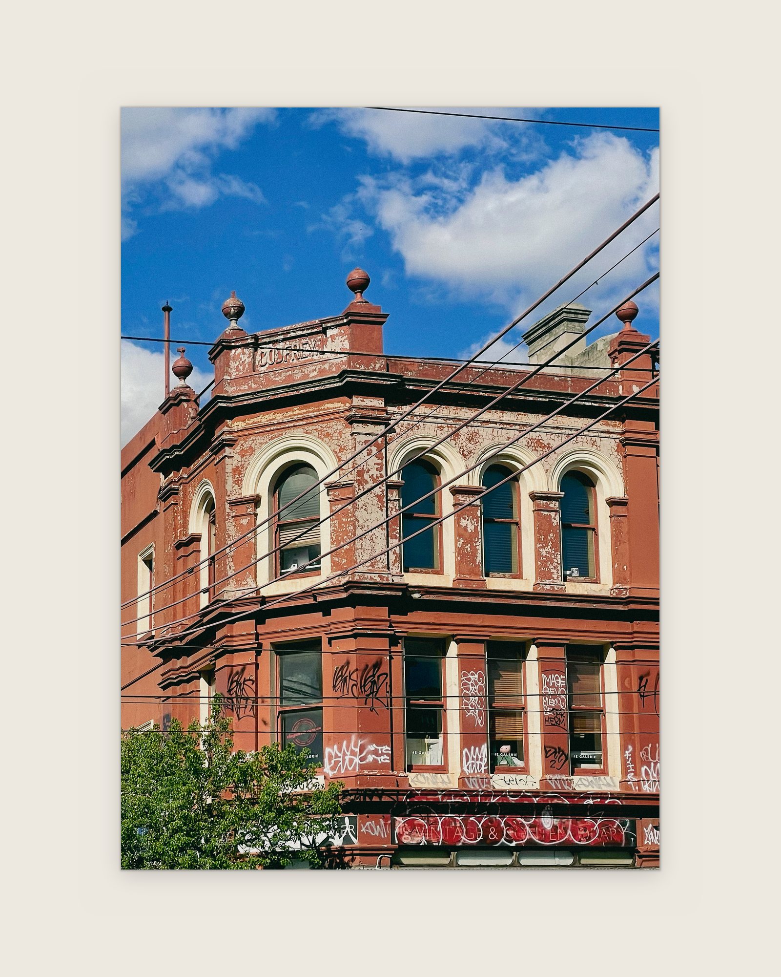 Red brick corner building with arched windows and parapet urns, Melbourne inner north, hidden__north documentary photography