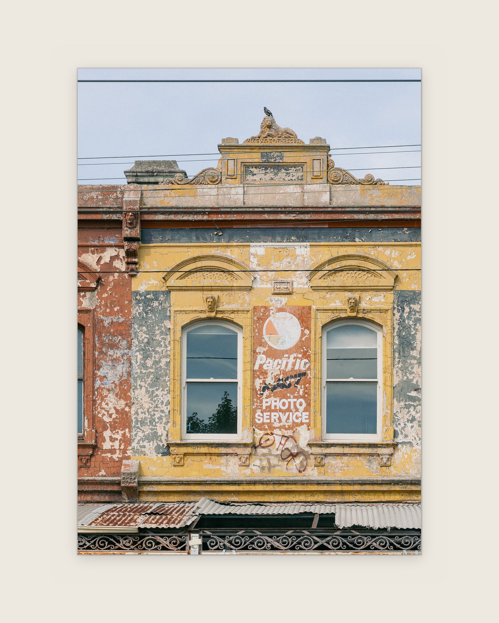 Ochre Victorian facade with arched windows and a Pacific Photo Service ghost sign, Carlton North, Melbourne inner north, hidden__north documentary photography