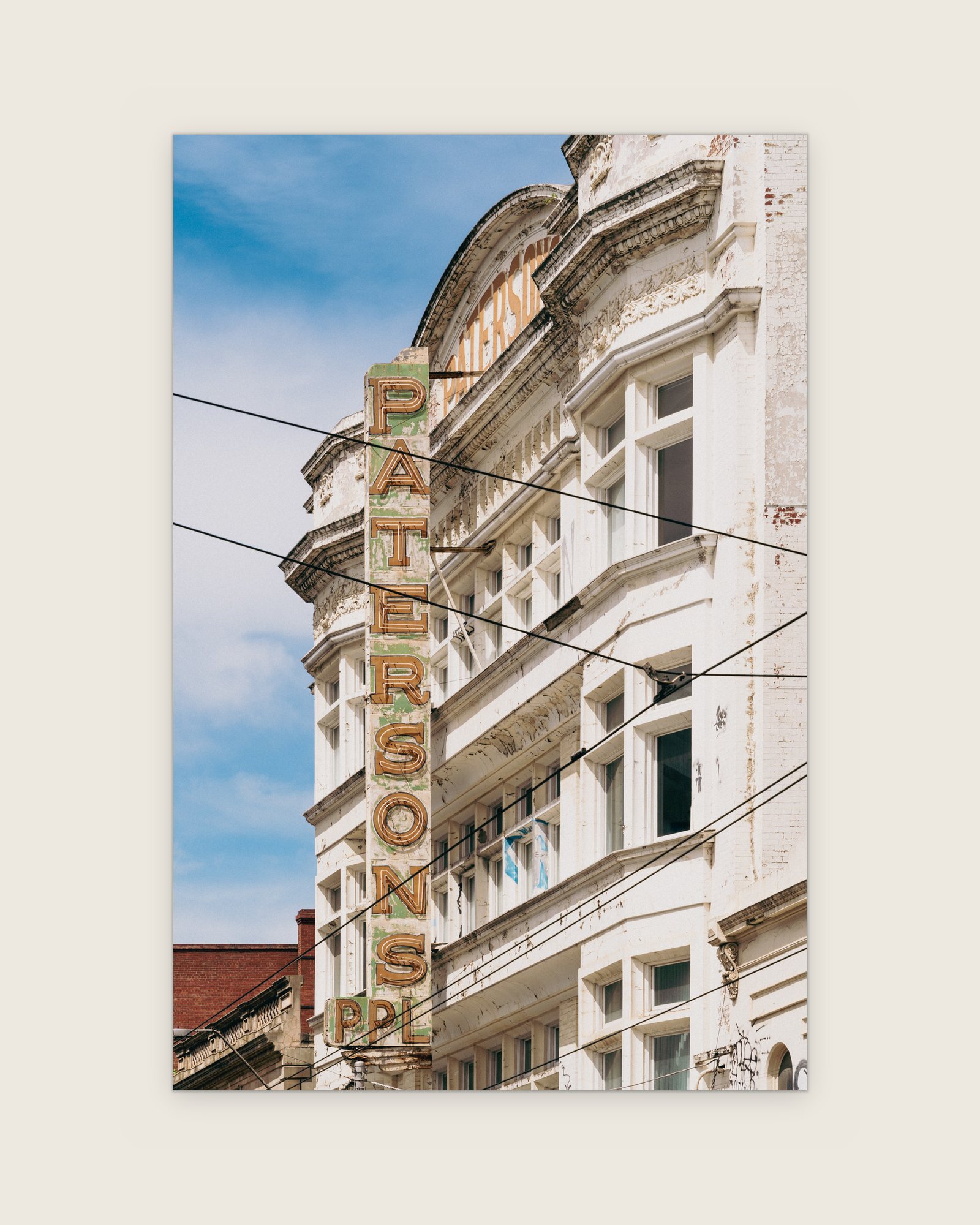 Vertical Patersons sign on a white ornate facade cut by overhead wires, Collingwood, Melbourne inner north, hidden__north documentary photography