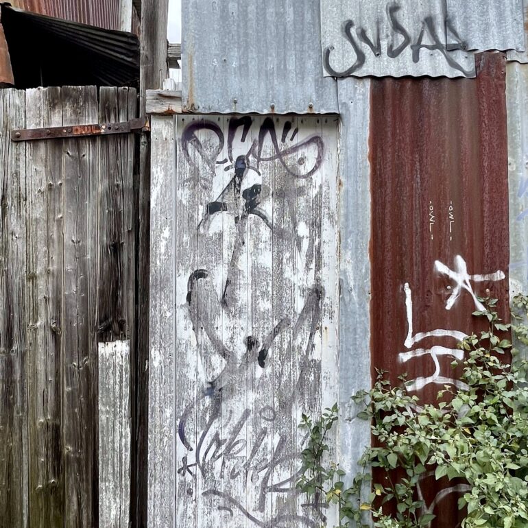 Weathered timber gate with stencil graffiti, Melbourne inner north, hidden__north documentary photography