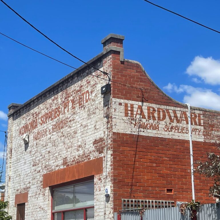 Faded Koinonia Supplies Hardware ghost sign on a whitewashed brick warehouse, Melbourne inner north, hidden__north documentary photography