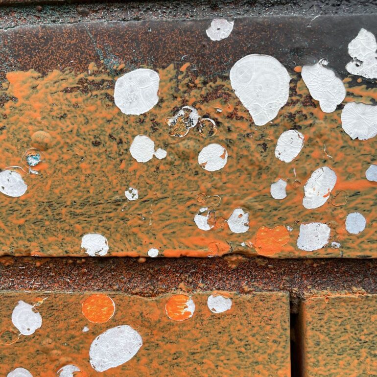 White paint splatter over orange rust and brick, Melbourne inner north, hidden__north documentary photography