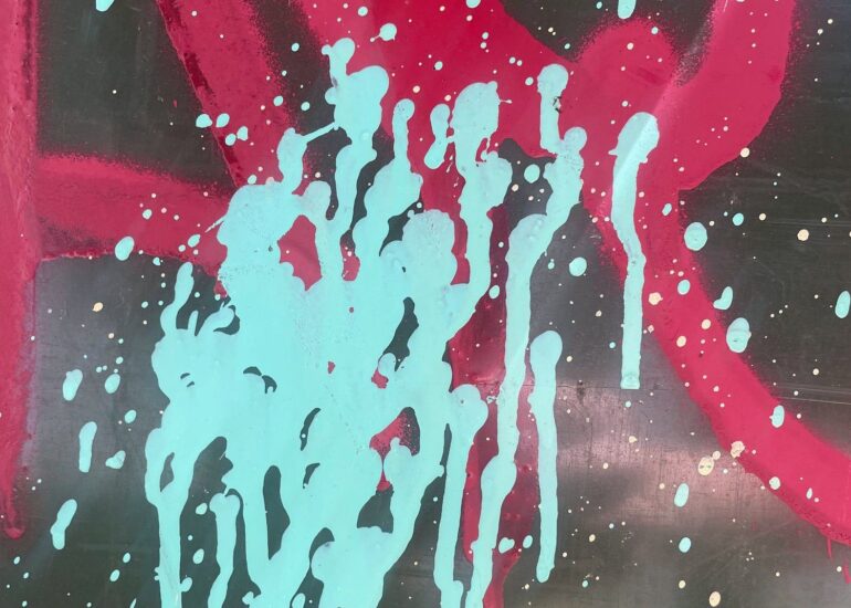 Mint paint drips over red spray swirls on a dark wall, Melbourne inner north, hidden__north documentary photography