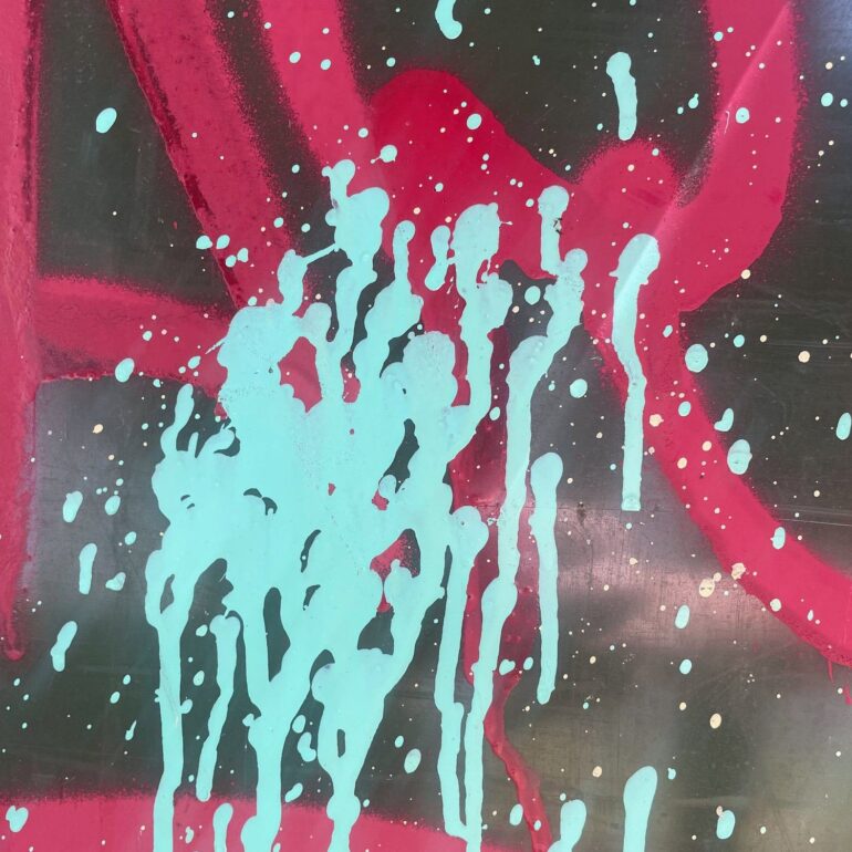 Mint paint drips over red spray swirls on a dark wall, Melbourne inner north, hidden__north documentary photography