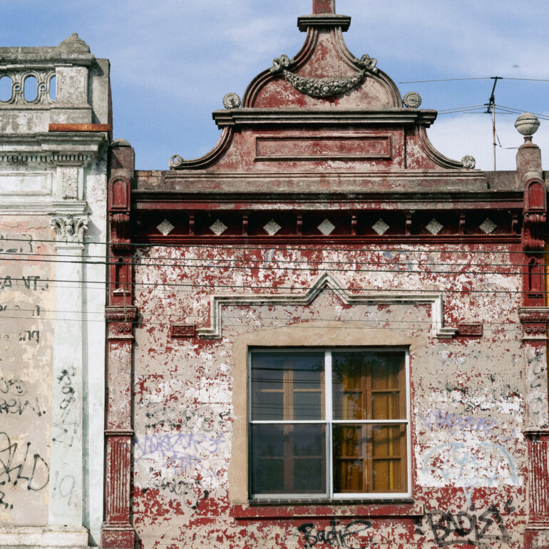 Victorian parapet with peeling red paint, Melbourne inner north, hidden__north documentary photography