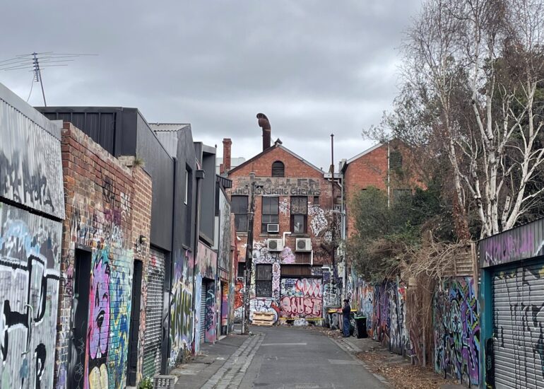 Graffiti covered laneway running toward a red brick building, Melbourne inner north, hidden__north documentary photography