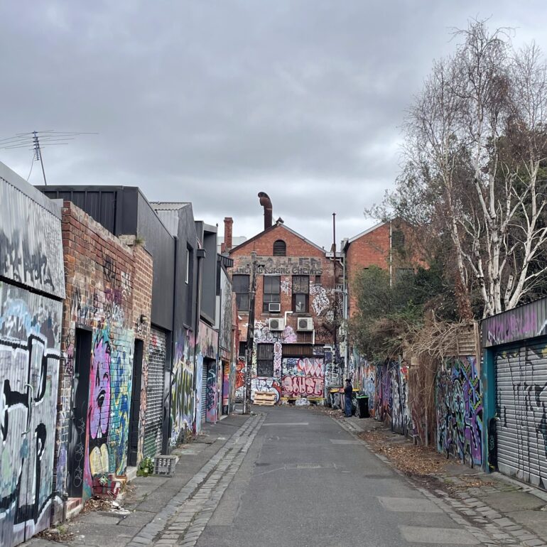 Graffiti covered laneway running toward a red brick building, Melbourne inner north, hidden__north documentary photography