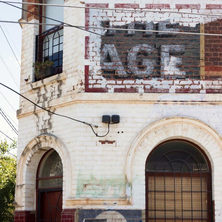 Faded The Age and Tarax ghost signs on a white painted corner building, Melbourne inner north, hidden__north documentary photography