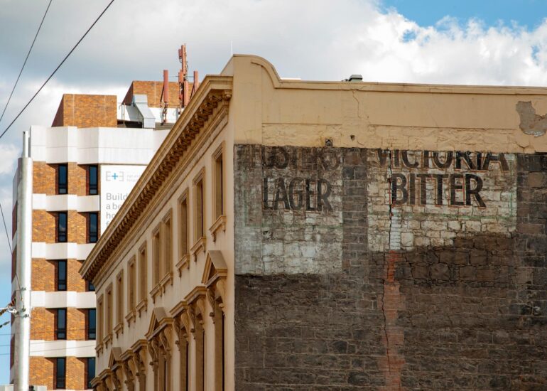 Victoria Bitter ghost sign on dark stone corner facade, Melbourne inner north, hidden__north documentary photography